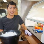 A student sitting at a table in a lab wearing gloves