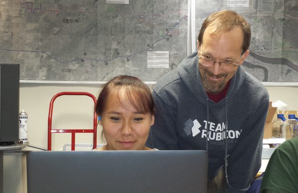 Don Stanley looking over the shoulder of students working on laptops