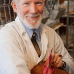 Mark Cook smiles for camera with a chicken in his arms