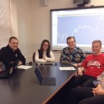 A group of people sitting around the end of a long conference room table.