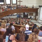 A group of hundreds of students fill a lecture hall.