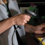 A woman using a barcode scanner type machine to scan the contents of a pea tree dish