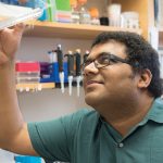 A man holding up a pea tree dish to look through it
