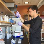 A man standing at a lab bench using equipment