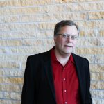 Paul Mitchell posed in front of brick wall