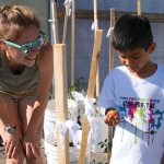 girl with a child as he tries a tomato