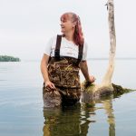 A woman standing in Lake Mendota with waders on