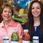 Two women sitting with bottled and canned beverages