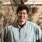 Kai Rasmussen standing in front of a wire grid wall with plants hanging from it.