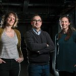 Three scientists standing together in a dark room