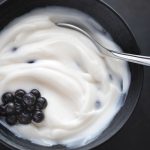 A bowl of yogurt with berries and a spoon in it
