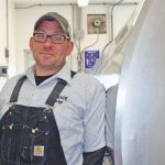 Andy Fisher stands by the 4,000-gallon bulk tank on his farm.
