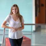 A woman leaning against the top of a clear glass staircase