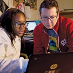 Lucas Rapisarda siting with a young woman in front of a laptop screen.