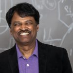 Srinivasan Damordaran smiling in front of a chalkboard