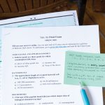 Image of a piece of paper with exam questions resting on a lecture hall desk.