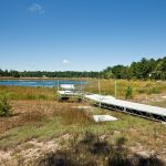 A drying lake bed on a sunny day, a dock stuck on land in the foreground.