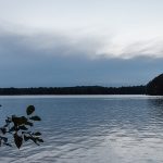 A still lake under low-lit, partly cloudy skies.