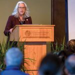 Dean Glenda Gillaspy stands at a podium in front of a crowd speaking.