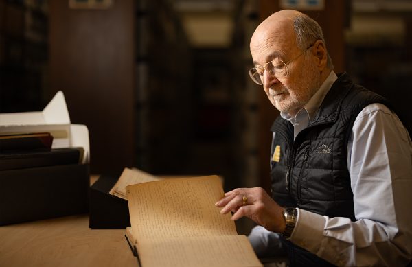 Stanley Temple sitting, flipping through the pages of an Aldo Leopold journal.