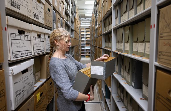 Katie Nash looking through files between the stacks of the UW Archives.