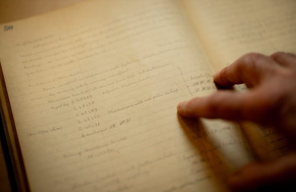 A close up of Stanley Temple's hand pointing at a page in an original Leopold journal.