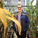 Jake Brunkard stands among tall plants in a UW greenhouse.