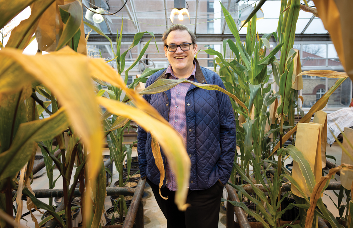 Jake Brunkard stands among tall plants in a UW greenhouse.