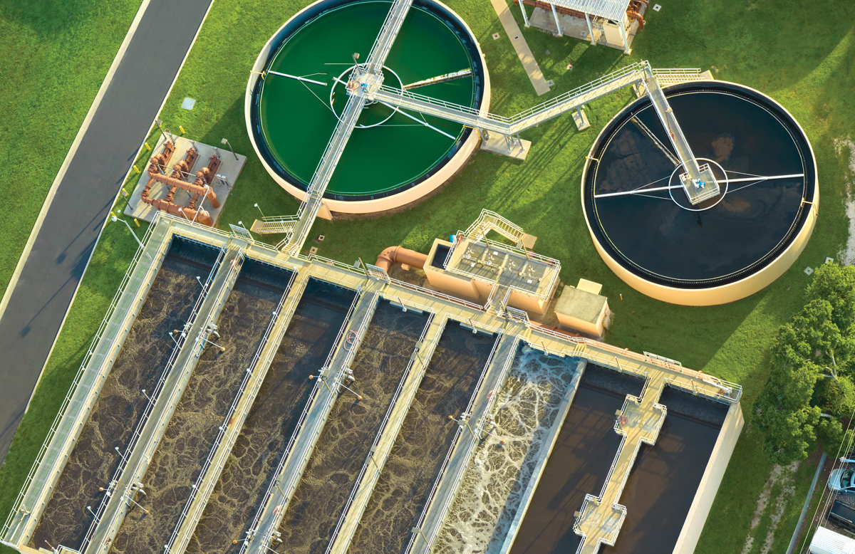 An aerial view of a facility. There are two large circular vats and large rows filled with water as well.