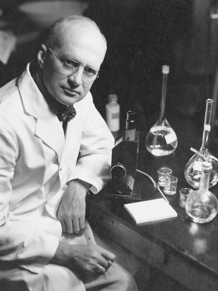 An old photo of Harry Steenbock sitting at a lab table.
