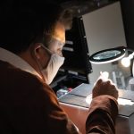 Tim Grant looking through a magnifying glass in a research lab.