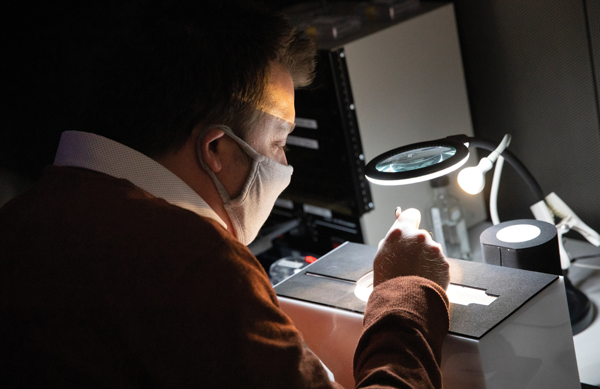 Tim Grant looking through a magnifying glass in a research lab.