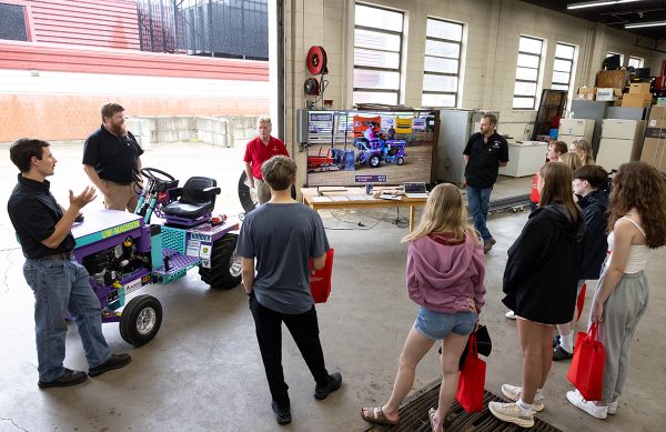 Students stand around a tractor and listen to people teach.