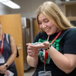 A student smiles as she holds a caterpillar in the palm of her hand