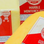 Three wedges of white and yellow Babcock cheese packaged in plastic.