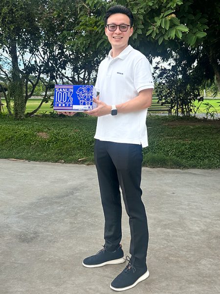 A man stands, posing with a box of coconut water