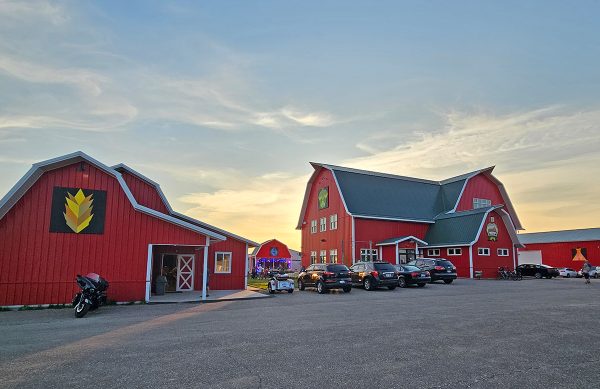 A series of buildings, designed to look like barns. There are cars parked outside. 